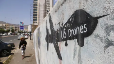 Getty Images A Yemeni man looks at graffiti protesting against US drone strikes on September 19, 2018