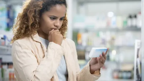 Getty Images woman buying pills at a pharmacy