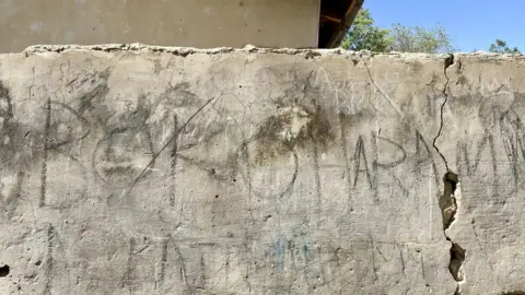 Kyla Herrmannsen/ BBC Faded Boko Haram graffiti on a wall in Damasak