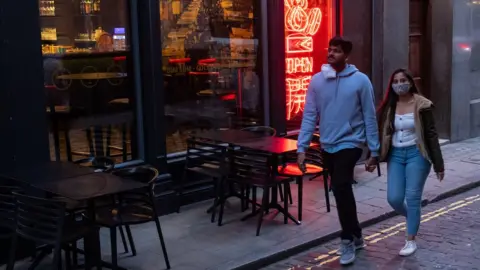 PA Media Couple walking past empty London restaurant