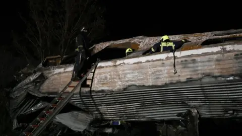 Getty Images A firefighter climbs up a ladder near the damaged train