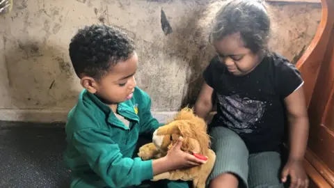 BBC Children pictured playing in front of a wall covered in mould