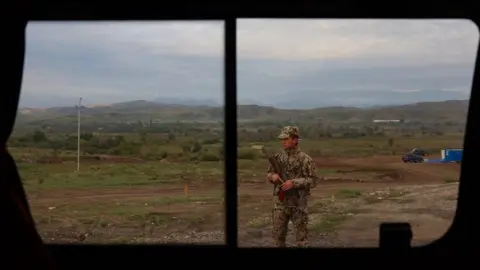 Getty Images An Azerbaijan police officer stands guard at a checkpoint along the border road in Agali, Zangilan district, on September 26