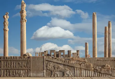 Getty Images Ruins of Apadana and Tachara Palace behind stairway with bas relief carvings in Persepolis Unesco World Heritage Site against cloudy blue sky in Shiraz, Iran