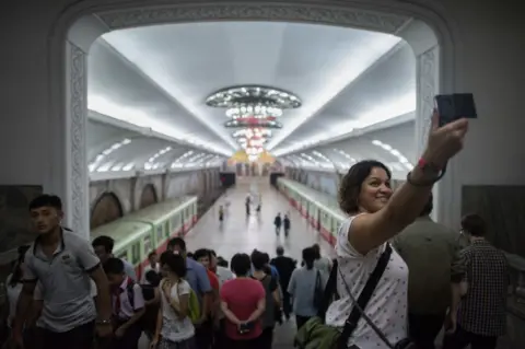 Getty Images A tourist takes a selfie during a visit to a subway station in Pyongyang on 23 July 2017.
