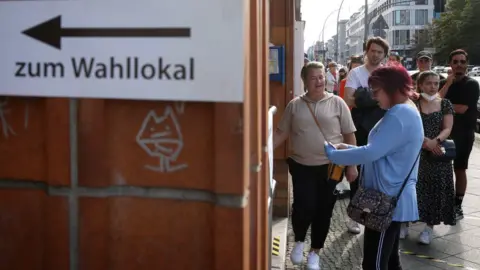 EPA People waits outside a polling station to vote in the German general elections in Berlin, Germany, 26 September 2021