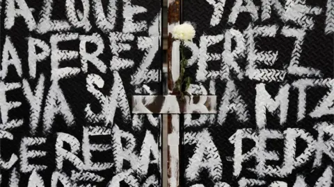 Reuters A flower is seen among the names of victims of femicide in Mexico painted by women on fences placed outside the National Palace ahead of a Women"s Day protest in Mexico City, Mexico March 7, 2021