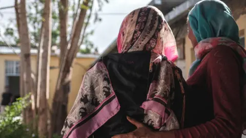 AFP A woman is held by an assistant at a safe house for survivors of sexual assault, in Mekelle in Tigray, Ethiopia - February 2021