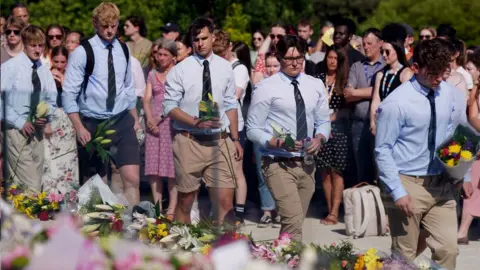 PA Media Barnaby Webber's team-mates laying flowers