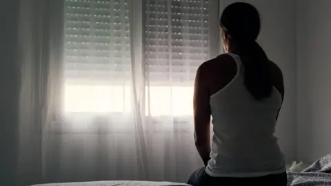 Getty Images A woman sits alone opposite a window