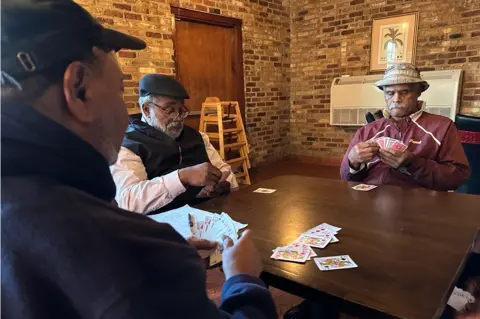 BBC Tyrone Dash, pictured left, plays cards with longtime friends in Orangeburg County at Dash's restaurant.