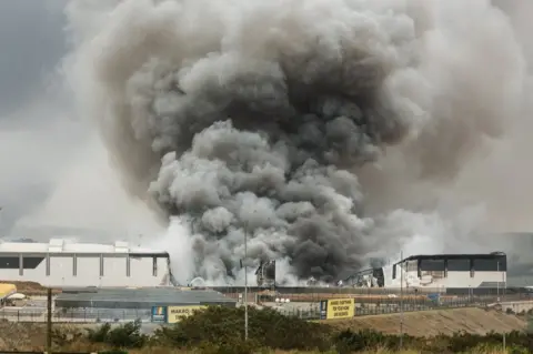 AFP Smoke rises from a Makro building set on fire overnight in Umhlanga, north of Durban, on 13 July 2021