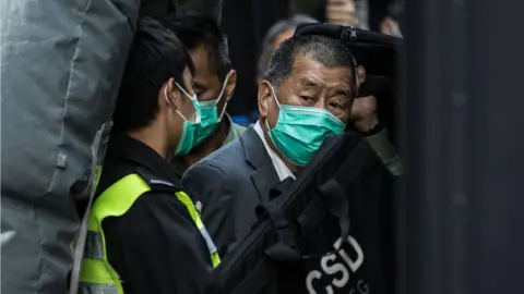 Getty Images Jimmy Lai escorted by police in 2021