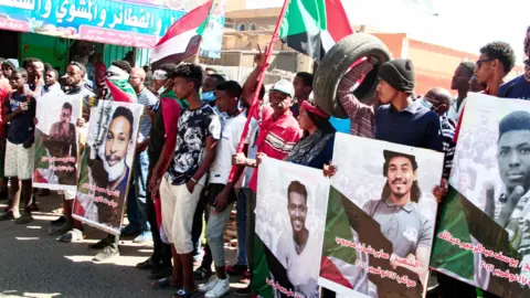 AFP Sudanese demonstrators carry posters of killed protesters in Khartoum - 30 December 2021