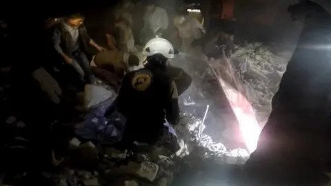 Syria Civil Defence Photo posted by the Syria Civil Defence, also known as the White Helmets, purportedly showing rescue workers after air strikes on Maarshurin, in the Syrian province of Idlib (20 December 2017)