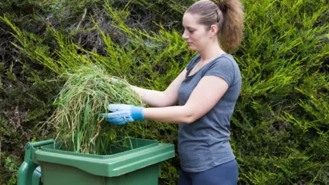 Getty Images A woman uses a green garden bin