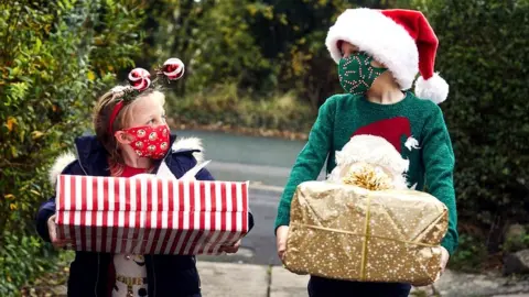 Getty Images Children with Christmas presents and face coverings