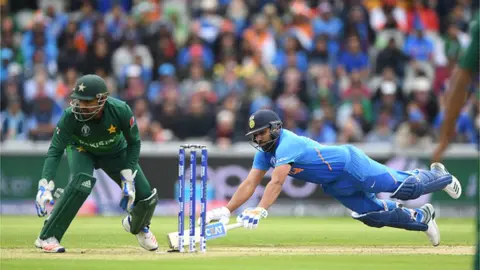 Getty Images Rohit Sharma of India dives to make his ground as Sarfraz Ahmed looks on during the Group Stage match of the ICC Cricket World Cup 2019 between India and Pakistan at Old Trafford on June 16, 2019 in Manchester, England.