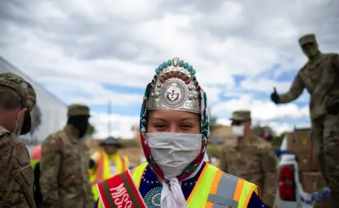 Getty Images Miss Navajo Nation Shaandiin P. Parrish puts on a white gown to help distribute food