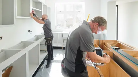 Getty Images Two men fitting a kitchen