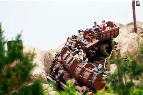 China News Service/Getty Images Riders wearing face masks are seen on the Seven Dwarfs Mine Train
