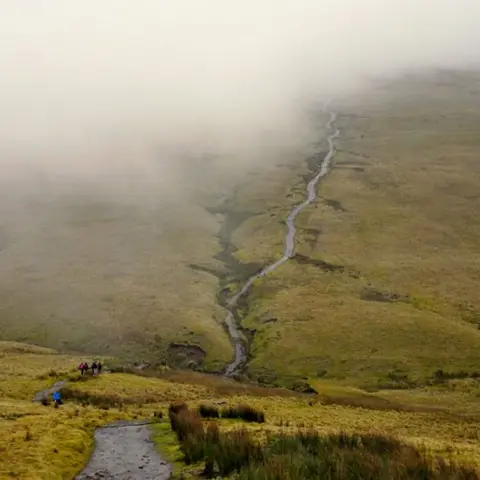 Alun Nevett Walkers head into the clouds on the path towards Corn Du in the Brecon Beacons