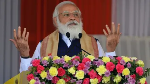 Getty Images Indian Prime Minister Narendra Modi gestures as he addresses a public meeting at Jerenga Pathar in Sivasagar district of India's Assam state on January 23, 2021.