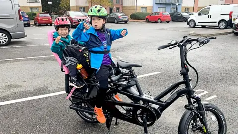 Gemma Loveless Two children on an e-cargo bike