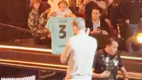 Gerard Pique heads over to sign a fan's shirt