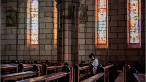 Getty Images A woman prays at the Immaculate Conception Cathedral in Madagascar's capital Antananarivo.