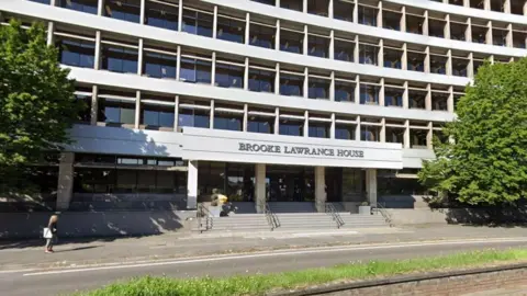 Google Exterior white building with black windows. Sign reads Brooke Lawrance House above the door.
