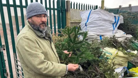 Lara King / BBC Nunny's Farm owner Neil Campbell holding a Christmas tree branch and a yew branch to show how similar they are