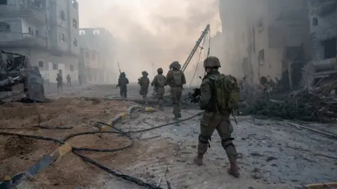 Reuters Israeli soldiers walk through rubble in the Gaza Strip