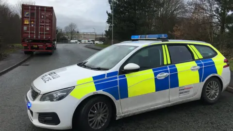 A police car blocking the road at the scene