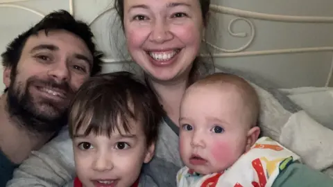 PA Media Paul and Lizzie Watson with children