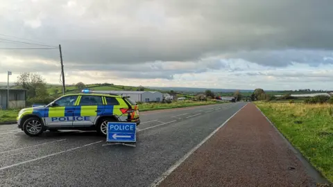 A police car blocks off a country road where the crash happened