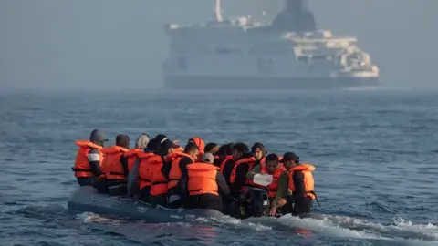 Getty Images An inflatable craft carrying migrant men, women and children crosses the shipping lane in the English Channel