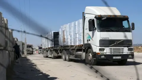 Reuters A lorry carrying goods passes through the reopened Kerem Shalom crossing in Rafah, in the southern Gaza Strip (25 May 2021)