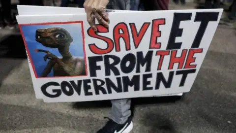 Reuters A person carries signs outside a gate to Area 51