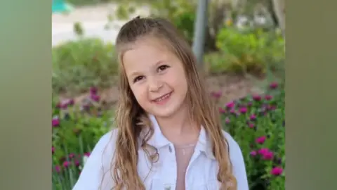 Yoni Asher Raz, the eldest daughter, smiles to camera