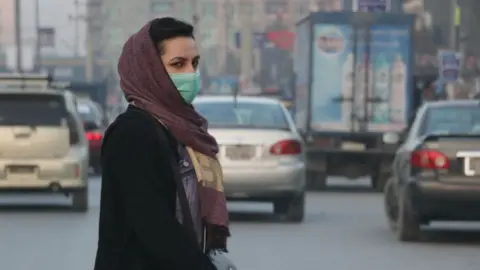 Getty Images An Afghan woman wears a face mask as she walks in a busy Bazar in Kabul, Afghanistan on December 23, 2020