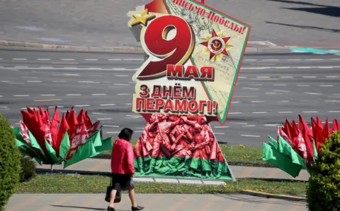 EPA A woman walks past a patriotic placard as Minsk prepares to celebrate Victory Day, 7 May 2020