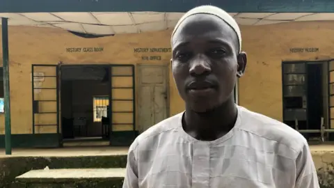 Nduka Orjinmo/BBC A man in front of a classroom