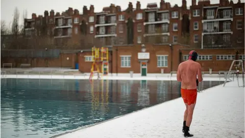 LEON NEAL/AFP via Getty Images Man walking away from pool at Parliament Hill Lido