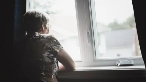 Getty Images a lonely woman looking out of a window