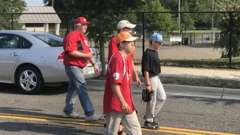 Anthony Zurcher Congressman Joe Barton, his two sons and Congressman Chuck Fleischmann walk by the baseball field targeted by a gunman.