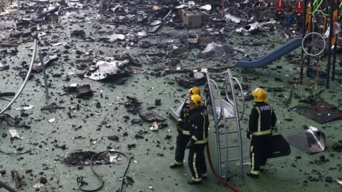 Reuters Firefighters stand amid debris in a childrens playground