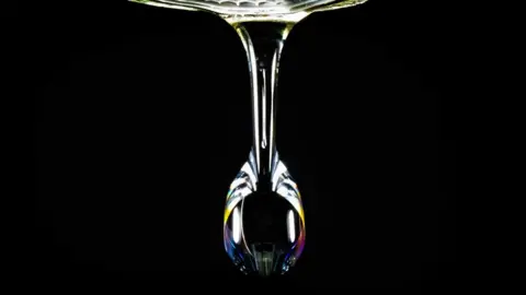 Dave Ranson Close up of a water drop showing an array of rainbow colours against a black background