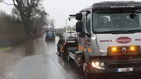 Lancashire Police Tractor driving in flooded road and vehicle being towed by truck