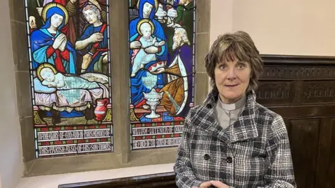 Nia Wyn Morris standing beside the church windows